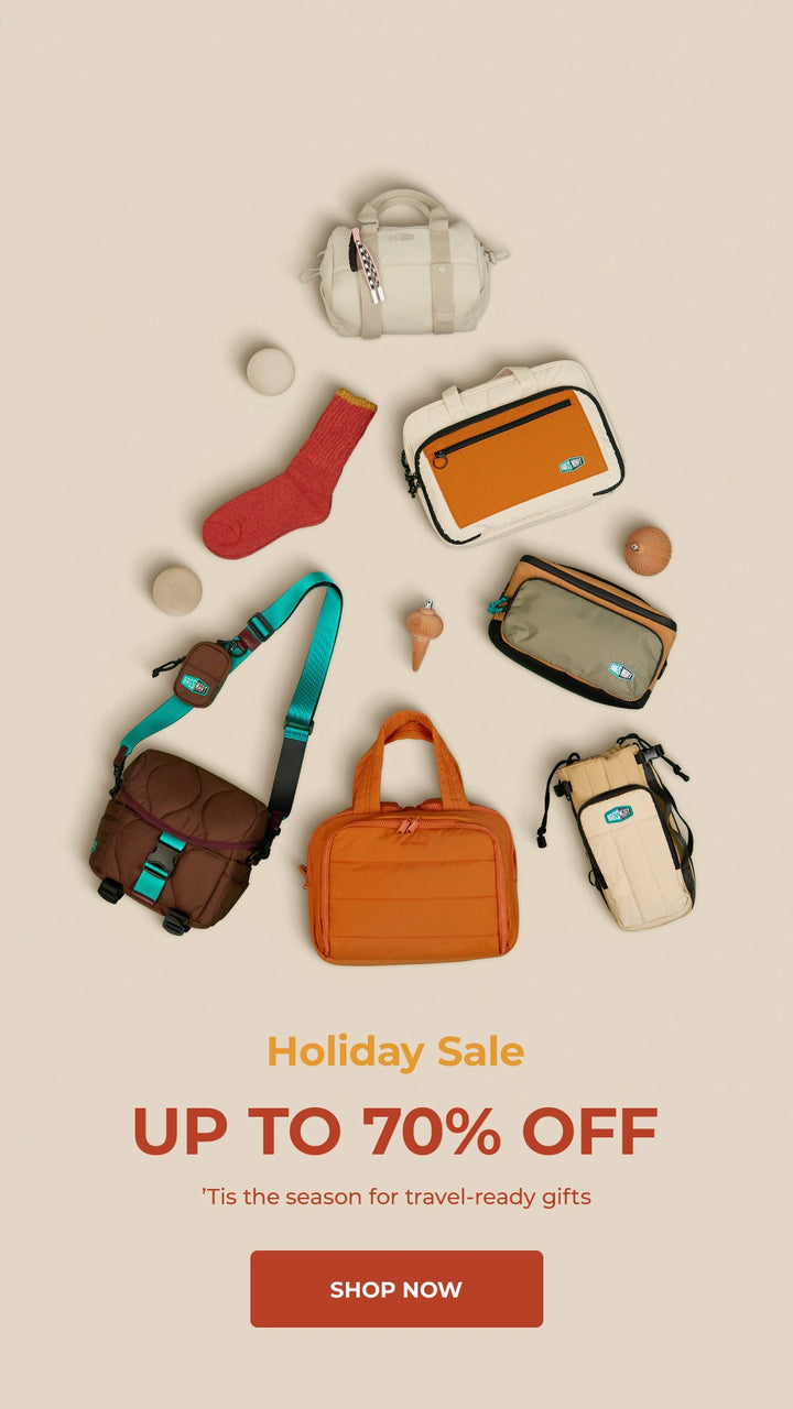 Collection of travel bags and accessories with a holiday sale promotion on a beige background.